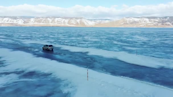 Βόλτες με αυτοκίνητο στον μπλε πάγο της λίμνης Baikal το χειμώνα. Προβολή από την πλευρά του Quadcopter — Αρχείο Βίντεο