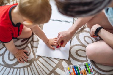 Genç bir anne ve küçük oğlu beraberce çizip oynuyorlar. Ailenle evde mutlu vakit geçirme kavramı. Çocukların bakımı