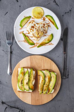 Beyaz bir tabakta kalp şeklinde kızarmış yumurta ve avokado sandviçi şeklinde güzel, sağlıklı, romantik bir kahvaltı. Yukarıdan görünüşü