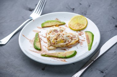 Avokado dilimleri ve beyaz bir tabakta limonla kalp şeklinde güzel, sağlıklı, romantik bir kahvaltı..