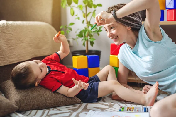 A young mother and child spend time together. They have fun, draw and play. Concept of a happy time with your family at home.