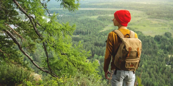 Turista Batohem Červeným Kloboukem Stojí Okraji Útesu Dívá Zelené Údolí — Stock fotografie