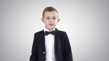Takım elbiseli arkadaş canlısı küçük bir çocuk merhaba diyor ve sonra arka planda hoşça kal diyor..