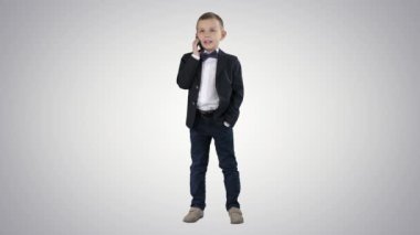 Akıllı telefonuyla konuşan sevimli küçük bir çocuk ve değişken arka planda koyu bir takım elbise içinde duruyor..