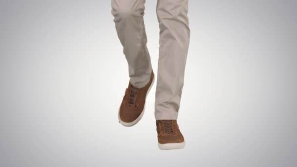 Hombres pies caminando en pantalones vaqueros beige y zapatillas de deporte marrones sobre fondo degradado . — Vídeos de Stock