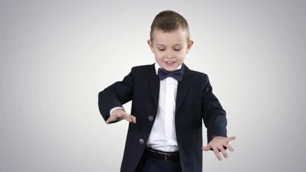 Pojke i en formell kostym sparkar fotboll på gradient bakgrund. — Stockvideo