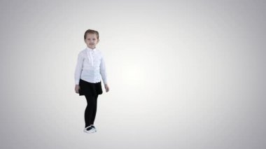 Sevimli küçük kız gülümsüyor ve özgüvenli bir şekilde arka planda kamerayla konuşuyor..