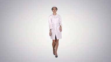 Beyaz elbise ve beyaz kask degrade arka plan üzerinde yürüyen kadın mühendis.