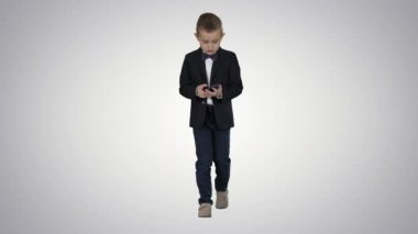 Kostüm yürüyüş ve degrade arka planda akıllı telefon kullanarak küçük çocuk.