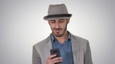 Akıllı, gelişigüzel Arap adam, gradyan arka planda yürürken akıllı telefon kullanıyor..