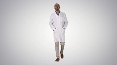 Arap yakışıklı doktor üniformasını giymiş, elleri cebinde, arka planda yürüyor..