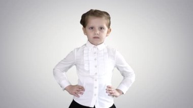 Küçük tatlı bir kız, elleri kalçasının üzerinde gradyan arka planda yürüyor..