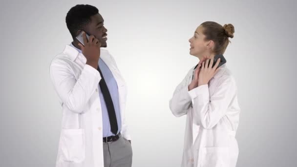 Médecin féminin et masculin utilisant des téléphones mobiles passer des appels annonçant de bonnes nouvelles sur fond de gradient . — Video