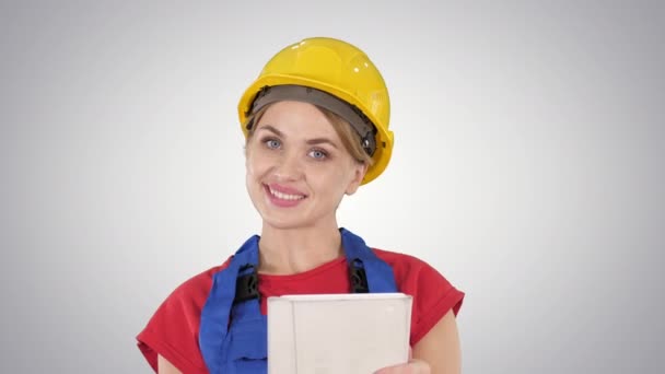 Tablet bilgisayarlı genç inşaat işçisi gradyan arka planda bir şey sunuyor. — Stok video