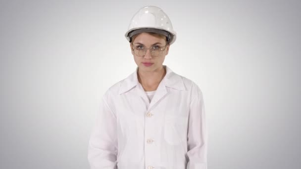 Young woman engineer in hard hat walking on gradient background. — Stock Video