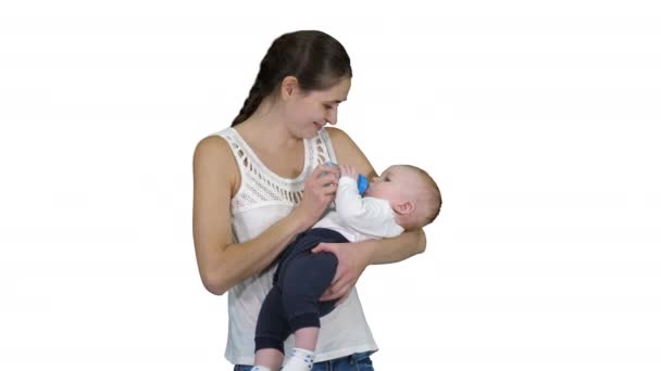 Mãe dá bebê para beber de garrafa no fundo branco . — Vídeo de Stock