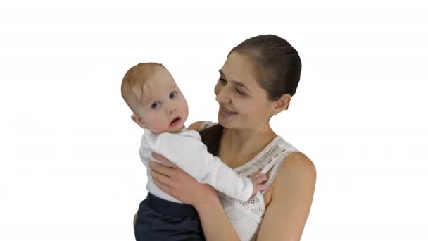 Matka drží své dítě a dívá se do kamery s úsměvem na bílém pozadí. — Stock video