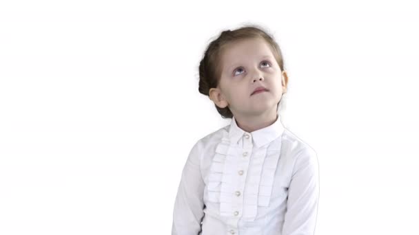 Cute przedszkola dziewczyna stoi nieśmiały patrząc wokół i myślenia na białym tle. — Wideo stockowe