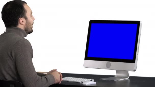 若いビジネスマン彼のコンピュータ上でビデオ通話を行う,白の背景.青い画面のモックアップ表示. — ストック動画
