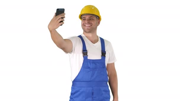 Sorrindo bonito jovem construtor fazendo selfie com telefone celular no fundo branco. — Vídeo de Stock