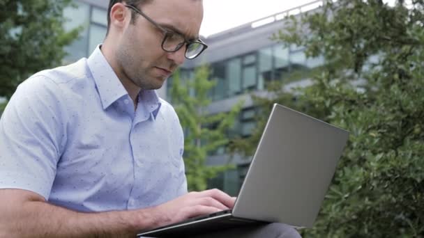 Wesoły człowiek pracuje na laptopie poza biurem. — Wideo stockowe
