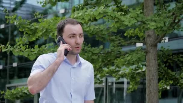 Junger Geschäftsmann telefoniert und geht. — Stockvideo