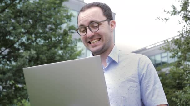 Emoção cómica. Homem de negócios nerd com sorriso louco trabalhando com seu laptop ao ar livre . — Vídeo de Stock