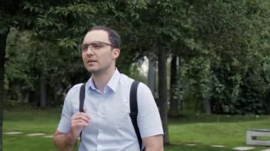 Sırt çantalı yakışıklı bir adam parkta bir şey ya da birini arıyor..