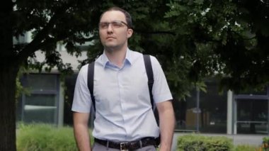 Yakışıklı iş adamı gözlük takıyor ve parkta yürüyor..