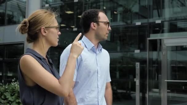 El hombre de negocios y una mujer caminando y hablando a lo largo del edificio . — Vídeo de stock