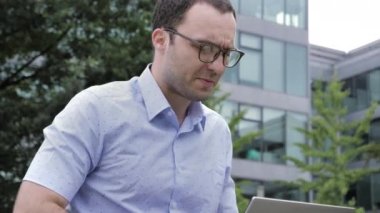 Handsome man working on his laptop outdoors.