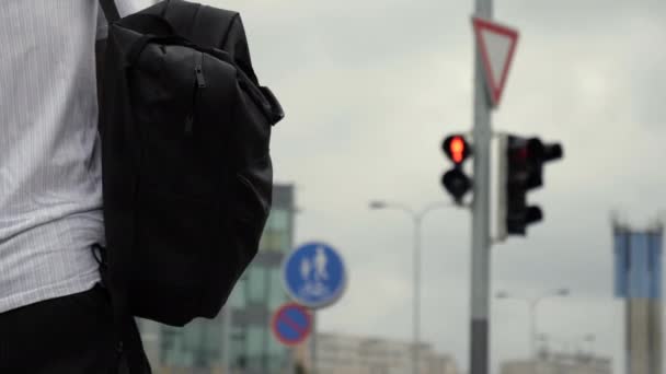 Jovem caminhando sobre uma luz verde carregando mochila e um saco . — Vídeo de Stock