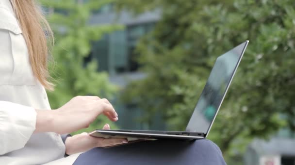 Vrouw handen met behulp van een laptop in een modern stadsgezicht. — Stockvideo
