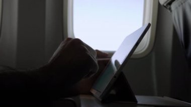 Uçakta modern dijital tablet kullanan erkek eller.
