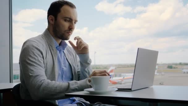 Man tänker i väntan på sitt flyg på den internationella flygplatsen sitter i ett café med sin bärbara dator öppnas. — Stockvideo