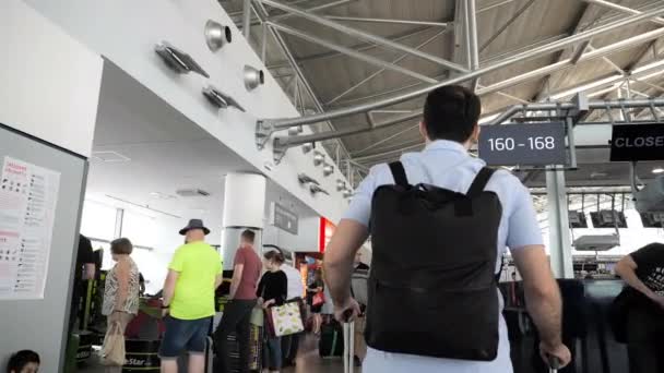 Prague, République tchèque. - 1er août 2019 : Homme marchant avec ses bagages et son sac à dos à la recherche d'horaires. Les gens sont partout autour de l'aéroport . — Video