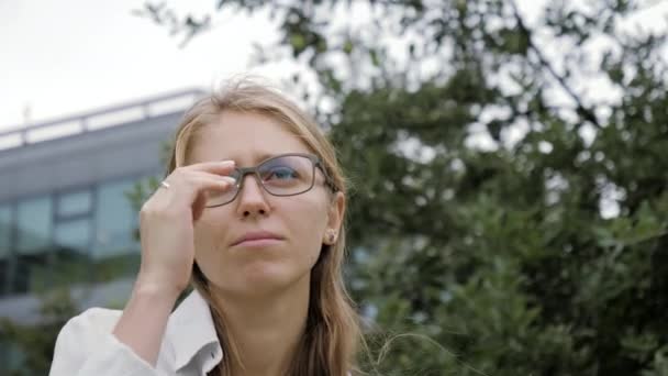 Νεαρή σοβαρή γυναίκα με γυαλιά κοιτάζει αλλού.. — Αρχείο Βίντεο