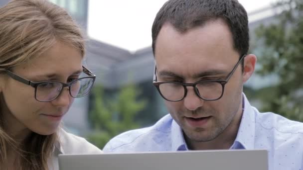 Feliz pareja de negocios utilizando el ordenador portátil al aire libre . — Vídeos de Stock