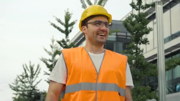 Joven ingeniero en gafas sonriente llevar un casco de seguridad siendo feliz por los resultados de su trabajo . — Vídeo de stock