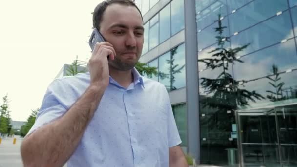 Atraktivní podnikatel mluví na mobilním telefonu, cítí radost, slyší dobré zprávy. — Stock video