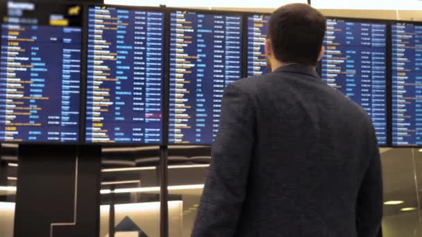Пассажир смотрит и указывает на расписание в аэропорту . — стоковое видео