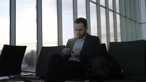 Young businessman waiting his fight at airport and fixing his wrist watch. — 비디오