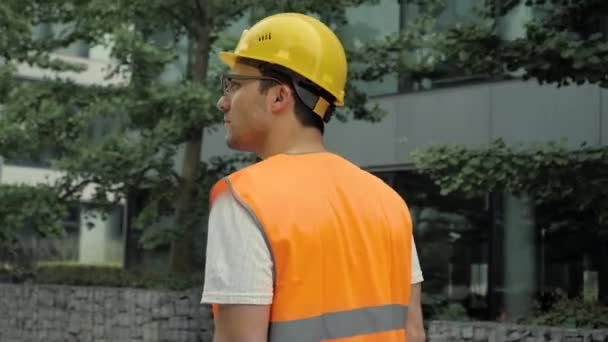 Jonge bouwkundestudent die langs het nieuwe gebouw loopt. — Stockvideo