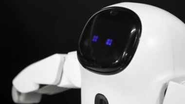 Small remote control toy robot with blue flashing eyes moves hands and body.