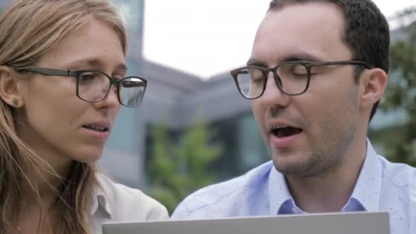 Young man and woman in glasses with laptop. — Stockvideo