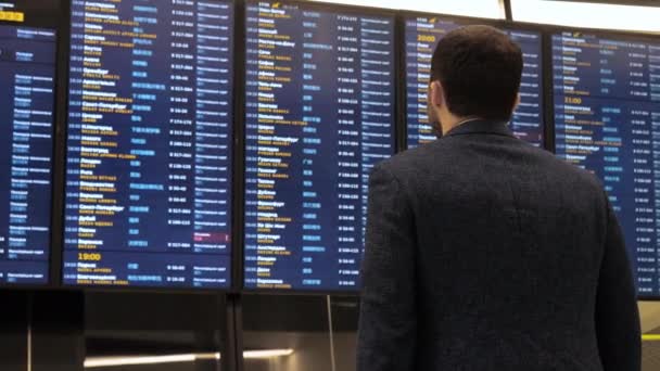 Pasajero mirando la pantalla de la tabla de horarios en el aeropuerto, vuelo internacional, hombre de negocios viaja al extranjero . — Vídeos de Stock