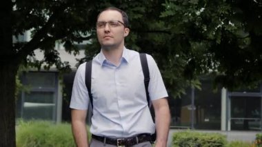 Yakışıklı iş adamı gözlük takıyor ve parkta yürüyor..