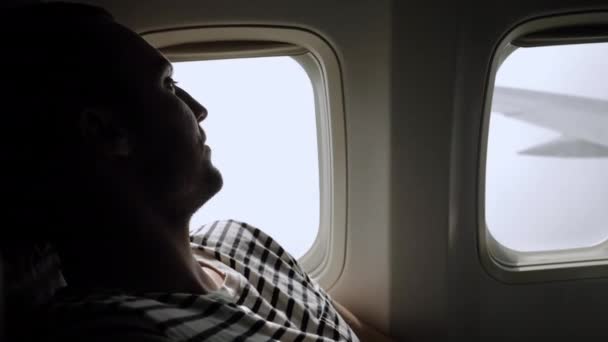Viajero viajero mirando a la ventana en avión, viaje en avión, hombre turista sentado en avión . — Vídeo de stock