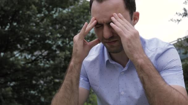 Feszült alkalmi férfi fejfájással Ül az épület előtt — Stock videók