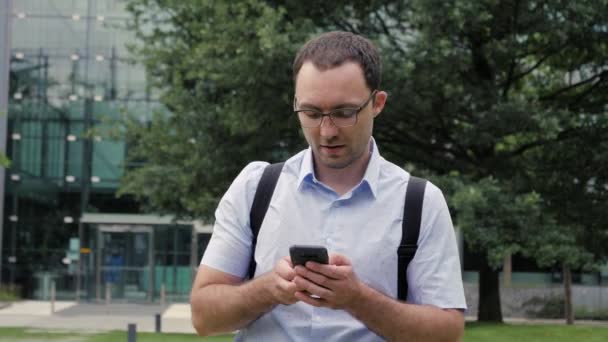 Mladý muž dotýká mobilní obrazovky na ulici. — Stock video